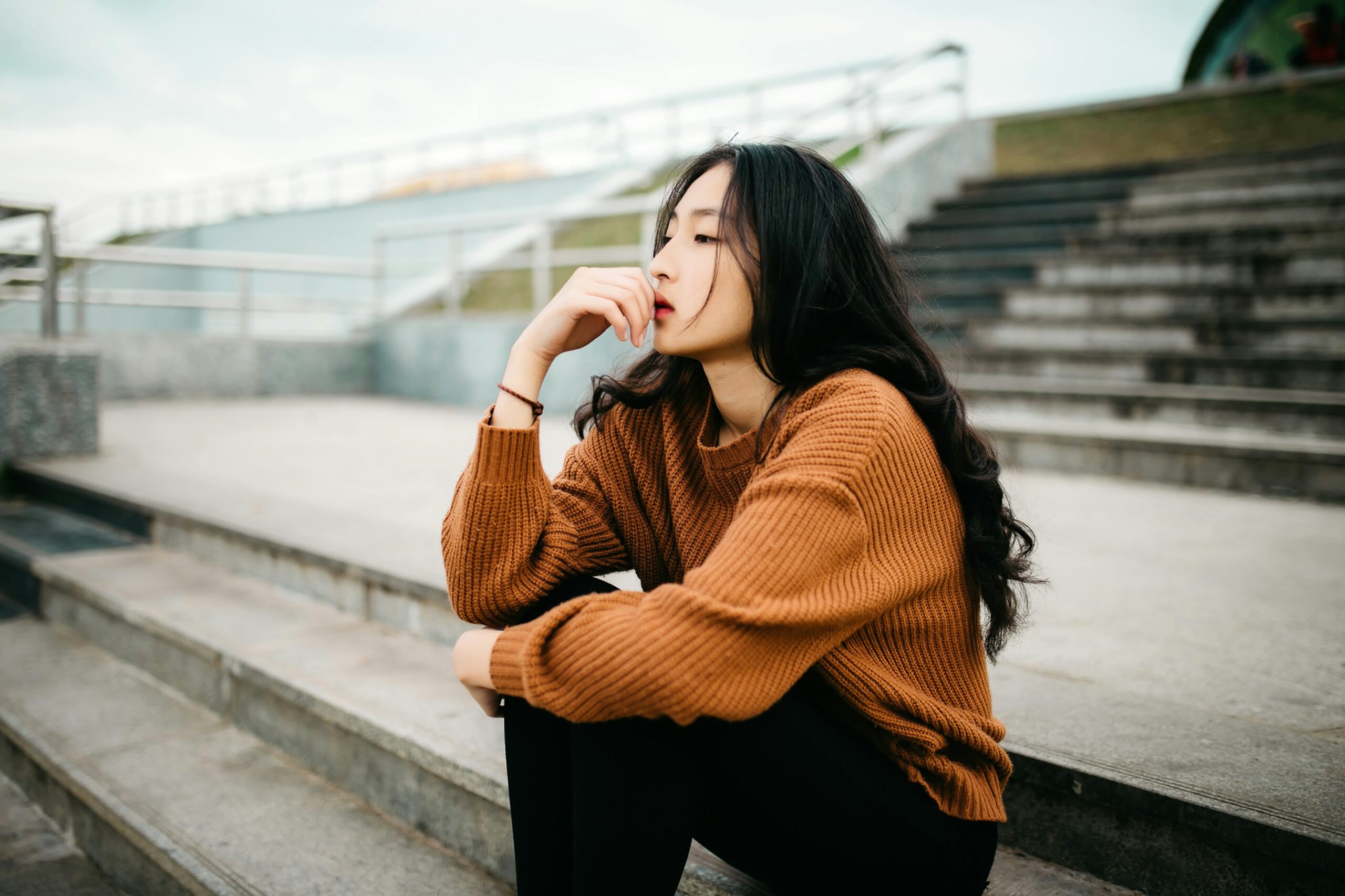 young woman sitting on bleachers thinking