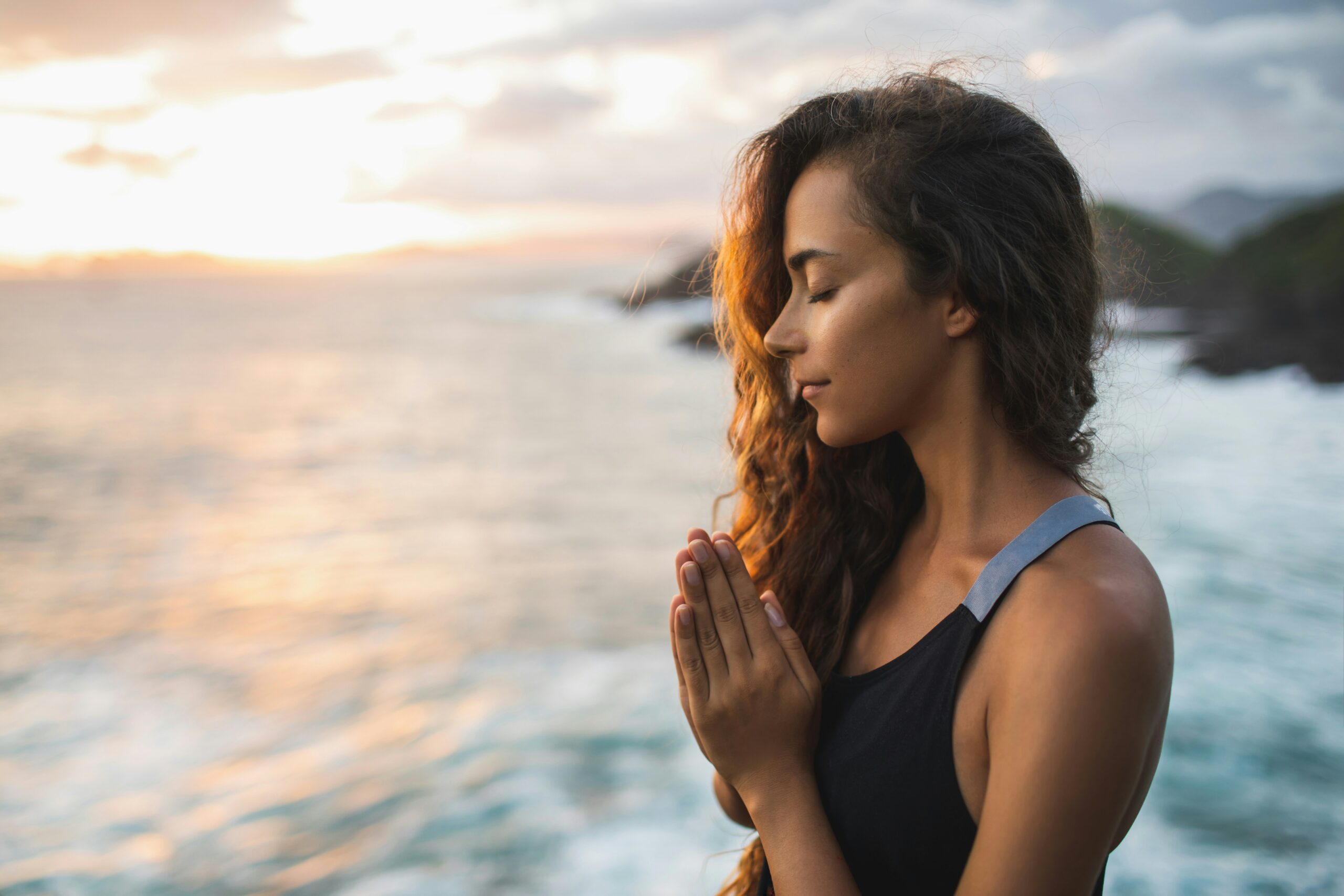Young woman praying by the beach